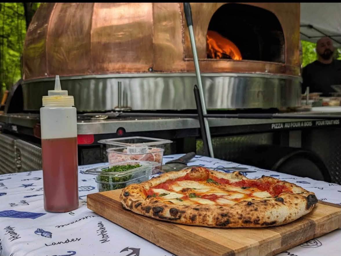 Pizza margherita napolitaine devant le four à bois en cuivre